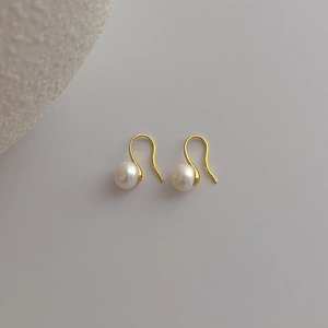 Detailed close-up of French minimalist gold ear hooks with round freshwater pearls