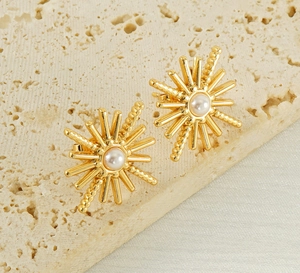 Détail de boucles d'oreilles perles en forme d'étoile avec rayons dorés sur pierre