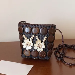 Close-up of bohemian woven coconut shell bag with cream flowers and cord strap
