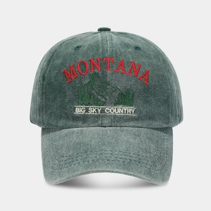Close-up of embroidered Montana mountain peak logo on washed vintage green baseball cap