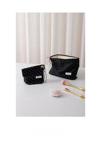 Close-up of black polka dot cosmetic bags with elegant pearl chain zipper details