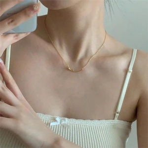 Close-up of golden bow-shaped pendant necklace worn by a model in a minimalist setting