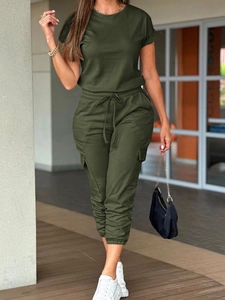Army green casual jumpsuit with short sleeves and drawstring waist in a corridor setting