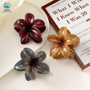 Detailed view of glossy flower hair claws in burgundy, amber, and smoke grey finishes