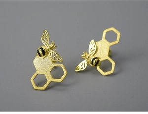 Macro detail of frosted gold honeycomb earrings with a delicate black coated honeybee