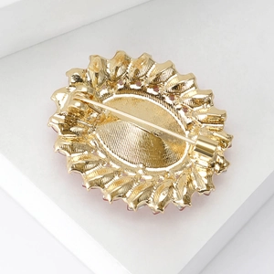 Back view of a gold sunflower crystal brooch with pin fastener on white background