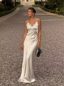 Elegant off-white satin long slip dress with lace neckline detail on model in garden