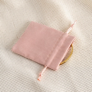 Pink velvet drawstring jewelry pouch with soft texture and golden ring accessory
