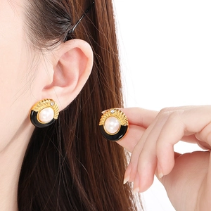 Boucles d'oreilles minimalistes dorées avec résine noire et perle portées par mannequin