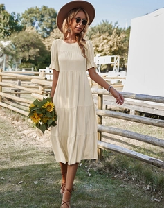 Détail d'une robe beige à manches courtes avec jupe à volants et encolure ronde classique