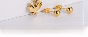 Close-up of golden butterfly earrings and spherical studs on white display stands