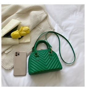 Detail of green shell-shaped crossbody bag with V-quilted faux leather and top handles