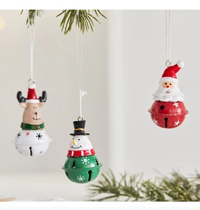 Close-up of Santa, snowman and reindeer metal bell ornaments hanging on pine branches