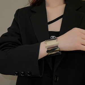 Polished wide metal cuff bracelet with wavy layers on a model wearing black suit