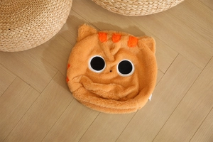 Vista dettagliata del cappello in peluche a forma di gatto arancione con grandi occhi