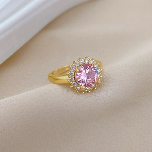Vue macro d'une bague ajustable en or avec une pierre rose ronde et un halo de zircons