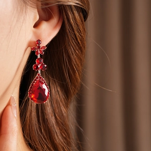 Close-up of red zircon flower waterdrop pendant earring on model for elegant gala