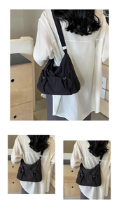 Detail of black nylon shoulder bag with adjustable drawstrings and metallic buckles