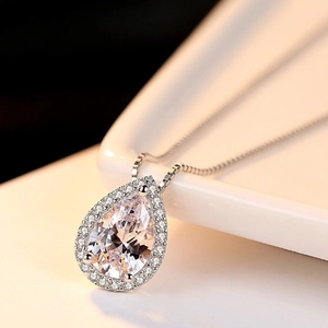 Macro view of teardrop necklace pendant with large crystal on white ceramic plate