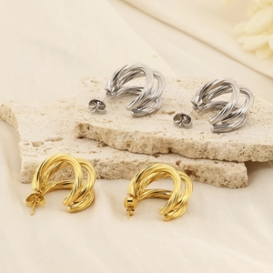 Close-up of gold and silver twisted C-shape earrings on elegant silk background