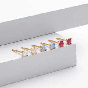 Three pairs of round-cut stud earrings in white, blue and rose red with gold four-prong settings