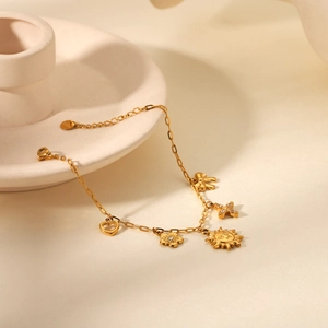 Macro detail of gold-plated charm bracelet showing S925 stamp and hollow heart pendant