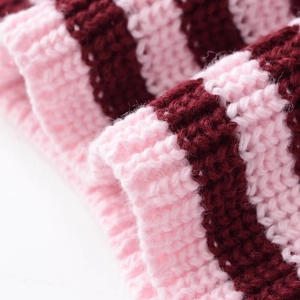 Dettaglio della trama in maglia a coste a righe rosa e bordeaux su un maglione retrò