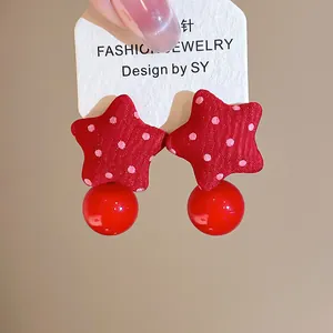 Detail of red fabric star earrings with white polka dots and a glossy round bead drop