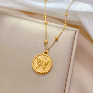 Macro detail of gold butterfly pendant on beaded titanium steel necklace on silk