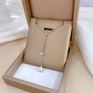 Detail view of a silver titanium steel star pendant Y-necklace on beige jewelry cushion