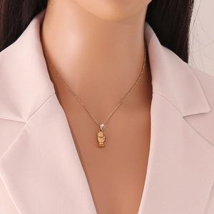 Detailansicht einer goldenen Hand-Halskette mit funkelndem Kristall an einem Model