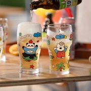 Close-up of glass beer mugs with cute cartoon prints being filled with cold drinks