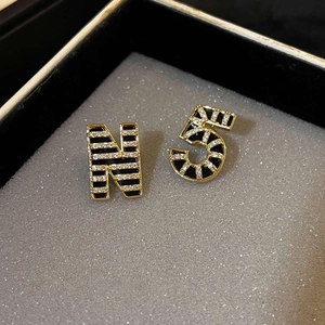Macro shot of 18K gold plated N and 5 earrings with black enamel and zircons