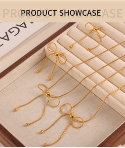 Detailed view of golden butterfly necklace and earrings set in a beige jewelry display box