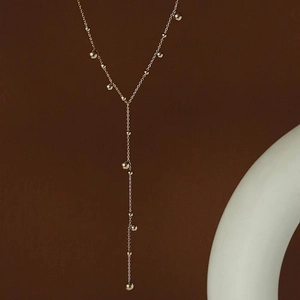 Elegant 18k gold plated Y-shaped lariat necklace with beads on a warm minimalist background