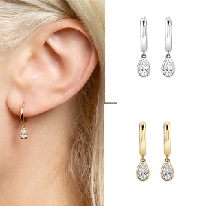 Macro view of teardrop zircon earrings with gold and silver hoop designs on model