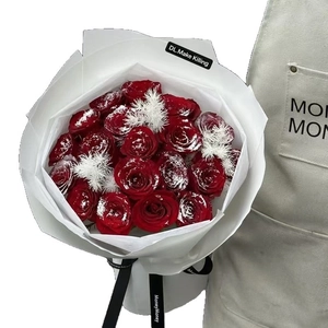 Mazzo di rose rosse artificiali con polvere di neve in confezione regalo bianca