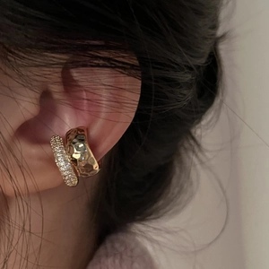 Detail of double-layered gold ear cuff with hammered texture and paved cubic zirconia