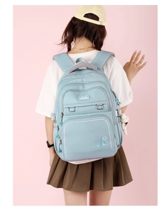 Close-up of light blue waterproof backpack with J.L.D logo and cute bear accessory