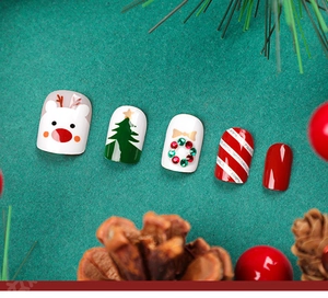 Close-up of festive Christmas press-on nails featuring reindeer, tree, and wreath patterns.