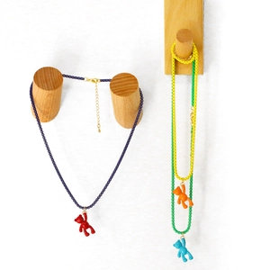 Detail of colorful teddy bear pendant necklaces on wooden hangers against white wall