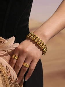 Detailed view of fashion gold beaded bracelet and gold smiley face ring on hand
