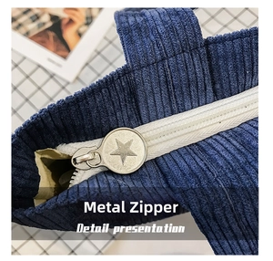 Close-up of star-embossed silver zipper on a dark blue corduroy shoulder bag detail
