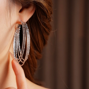 Side view detail of silver multi-layered hoop earrings worn with textured metal finish