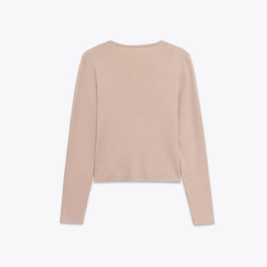 Close-up of beige knit sweater showing ribbed texture and lace patchwork detail