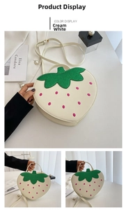 Detail of creamy white strawberry-shaped crossbody bag with green glitter leaf and top handle