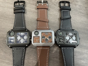 Tre orologi al quarzo Oulm oversize con doppio fuso orario e cinturino in pelle su legno