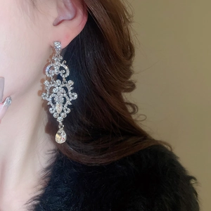 Detail view of Baroque drop earrings with white crystals and silver hollow patterns
