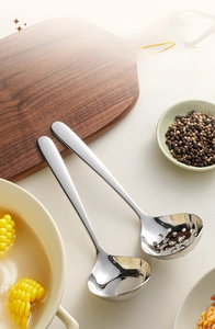 Macro shot of mirror-polished 304 stainless steel soup and slotted spoons in a kitchen setup