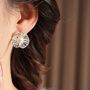 Macro shot of silver flower earrings with sky blue enamel details and white pearl